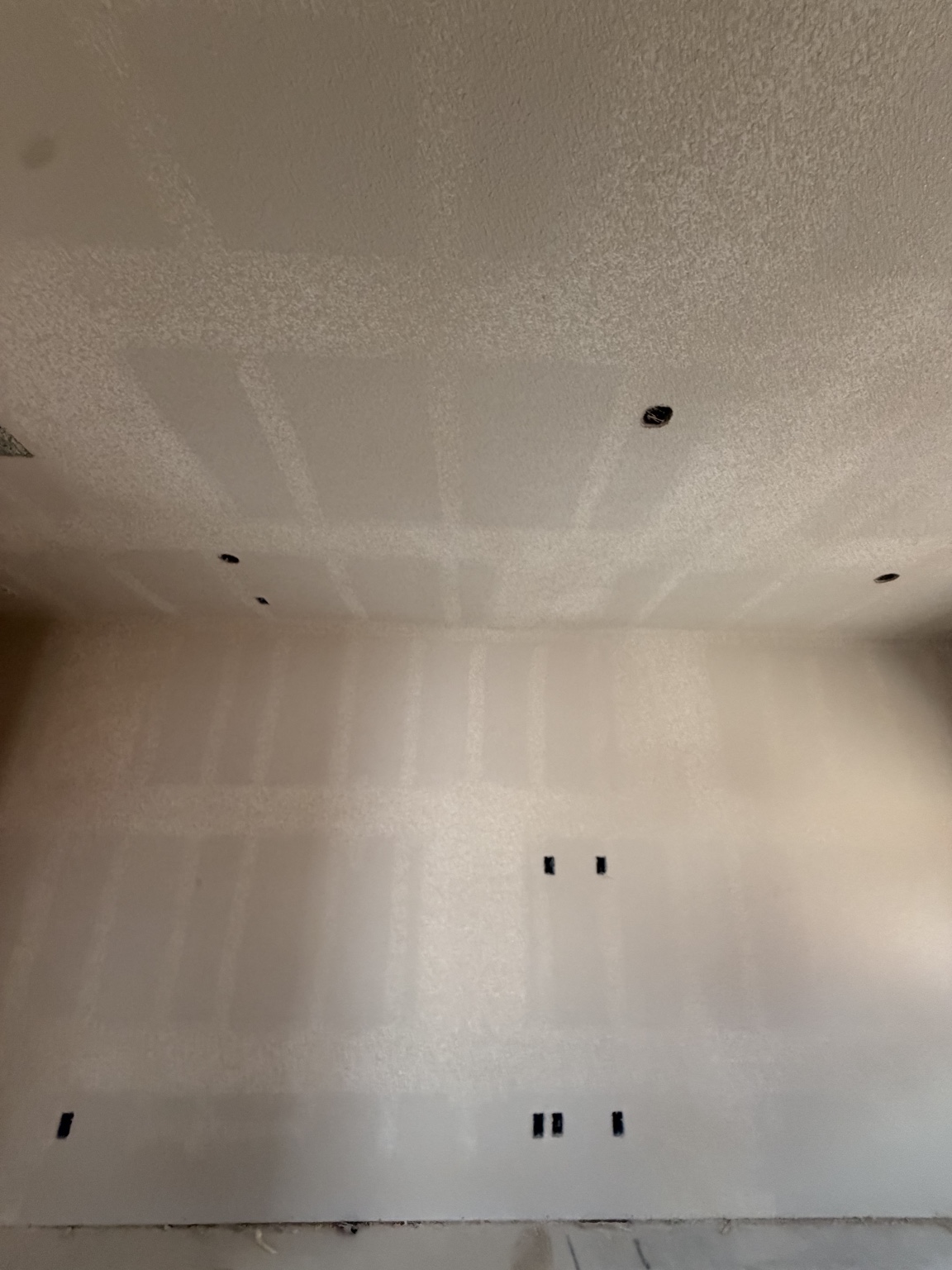Close view of textured ceiling and finished drywall wall