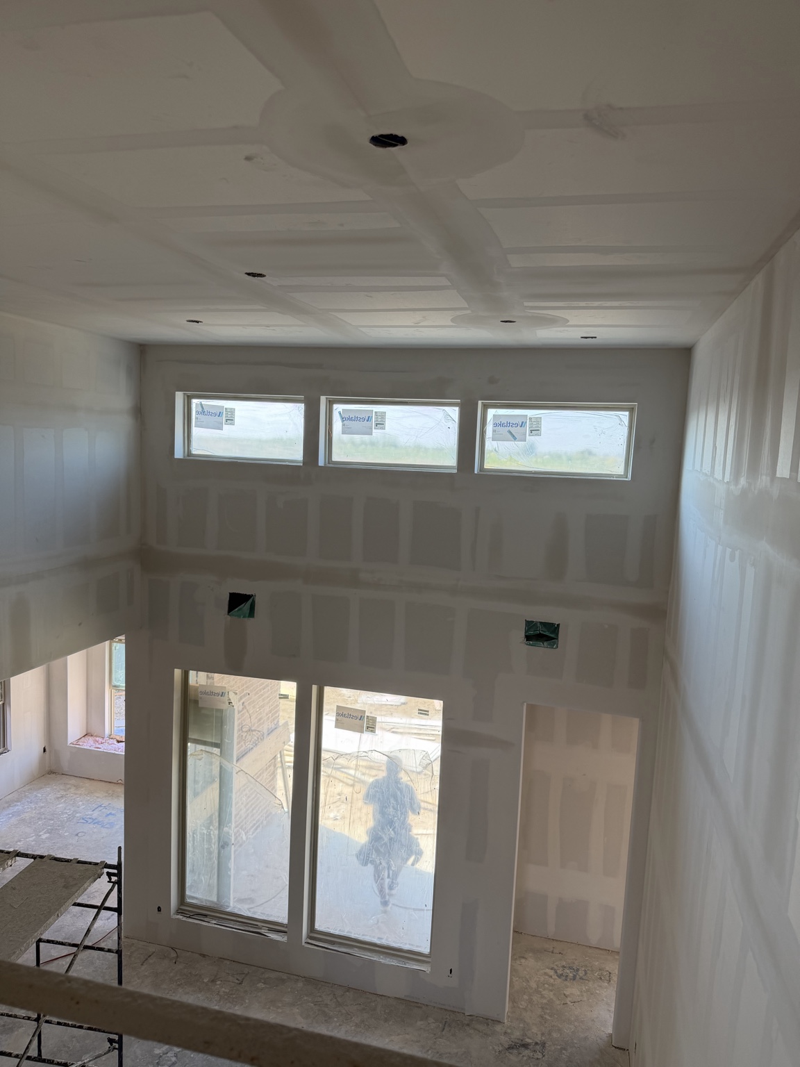 Two-story room with taped and bedded drywall
